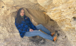 Image of Ronda Miller sitting inside a rock formation.